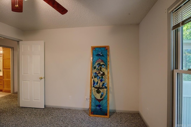 carpeted spare room featuring a textured ceiling and ceiling fan