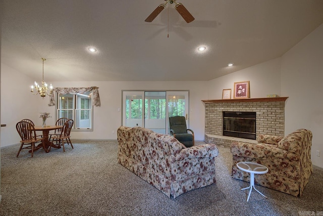 living room featuring lofted ceiling, ceiling fan with notable chandelier, a brick fireplace, a textured ceiling, and carpet floors