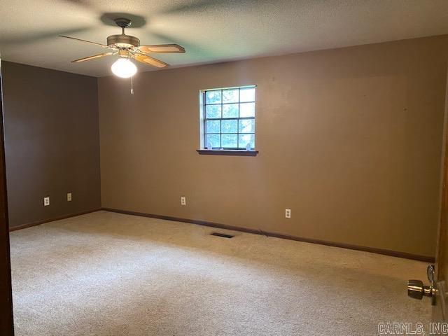 spare room with ceiling fan, light colored carpet, and a textured ceiling