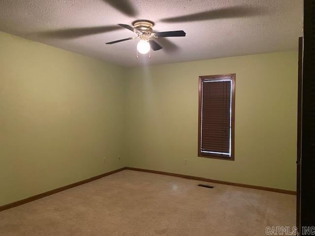 spare room featuring a textured ceiling, ceiling fan, and light carpet