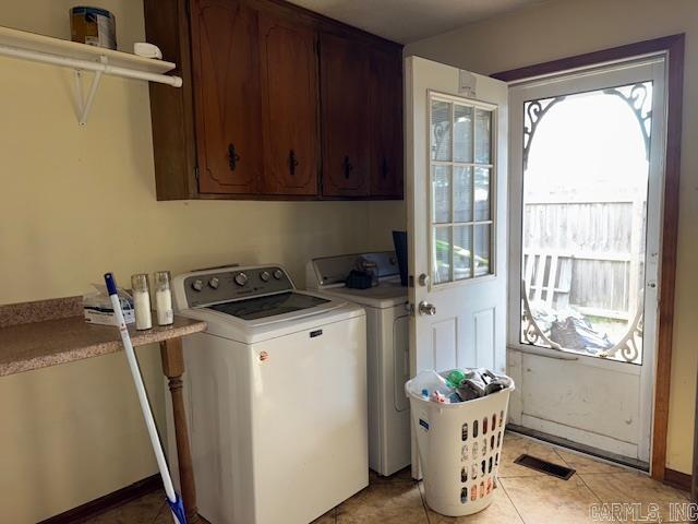 washroom with washer and clothes dryer, light tile patterned floors, and cabinets