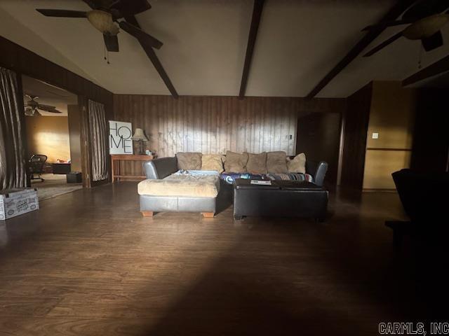 living area featuring wooden walls, dark hardwood / wood-style flooring, ceiling fan, and lofted ceiling