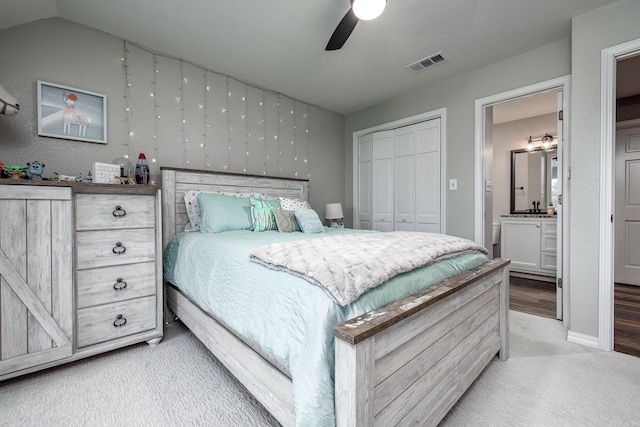 bedroom with connected bathroom, ceiling fan, a closet, and light colored carpet