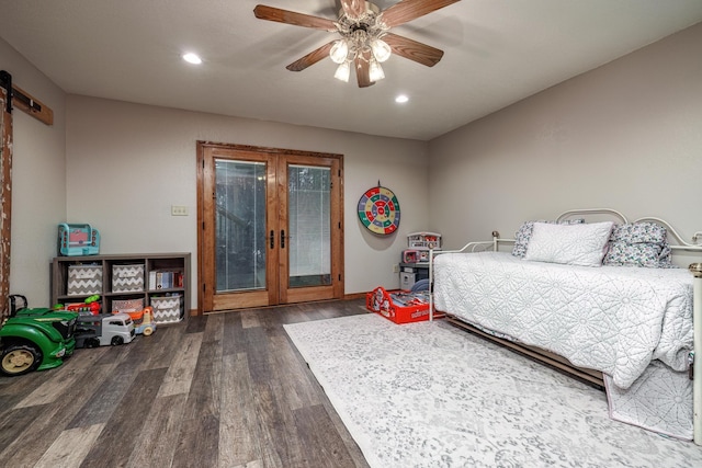 bedroom featuring a barn door, ceiling fan, dark hardwood / wood-style flooring, and french doors