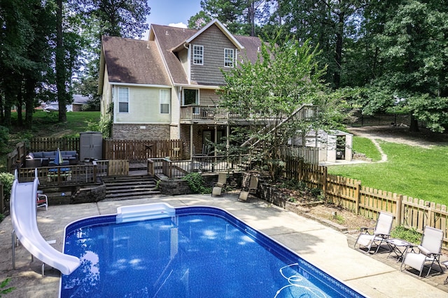 view of swimming pool featuring a lawn, a wooden deck, and a water slide