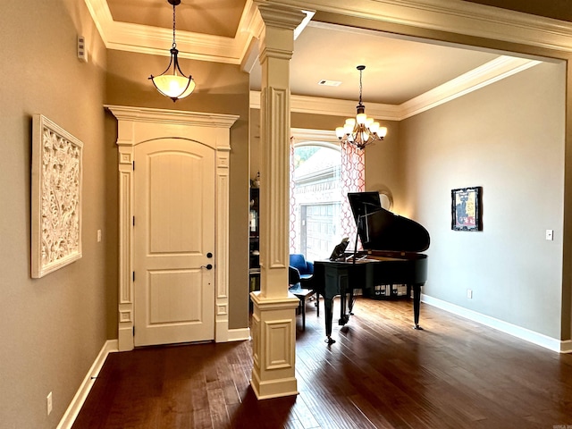 entryway featuring a chandelier, dark wood-type flooring, ornate columns, and crown molding