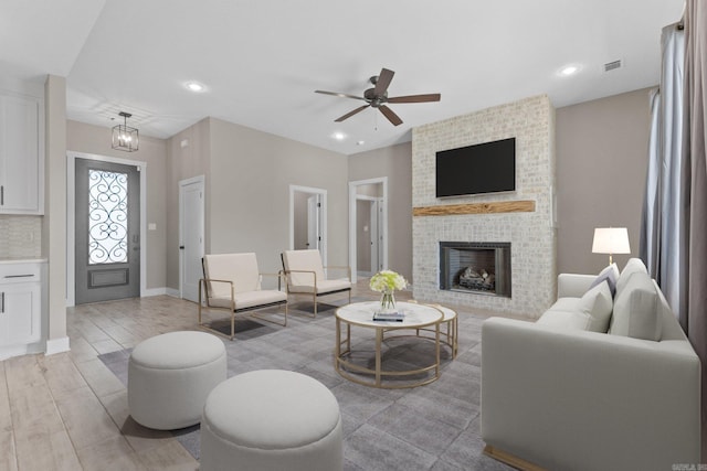 living room with ceiling fan, light hardwood / wood-style floors, and a brick fireplace