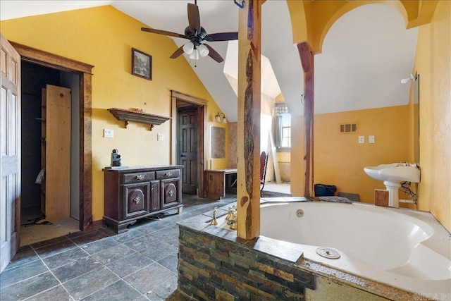 bathroom with a relaxing tiled tub, vaulted ceiling, and ceiling fan