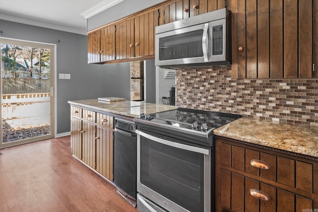 kitchen featuring crown molding, light hardwood / wood-style flooring, appliances with stainless steel finishes, tasteful backsplash, and light stone counters