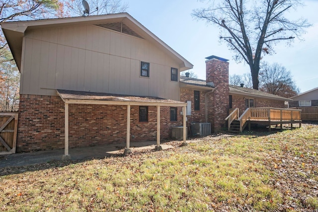 back of property with a lawn, a wooden deck, and central AC