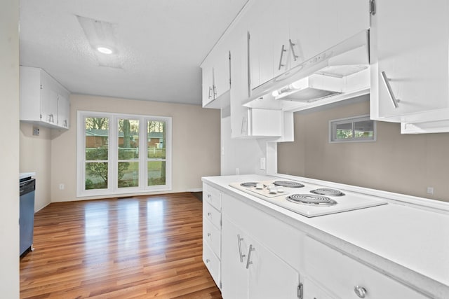 kitchen with stainless steel dishwasher, white cooktop, a textured ceiling, light hardwood / wood-style floors, and white cabinets