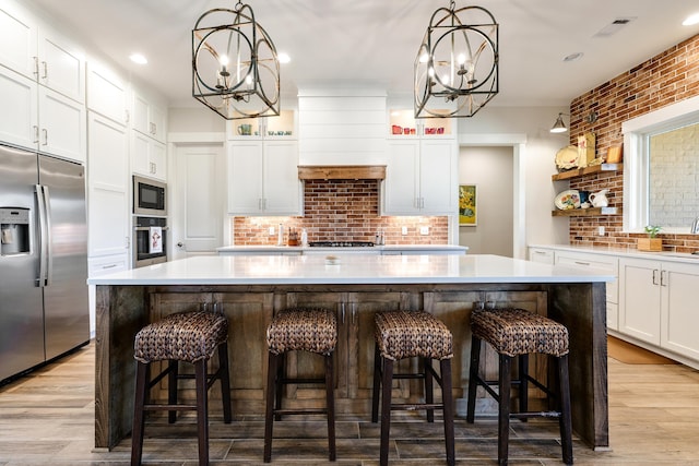 kitchen featuring white cabinetry, a chandelier, a center island, and stainless steel appliances