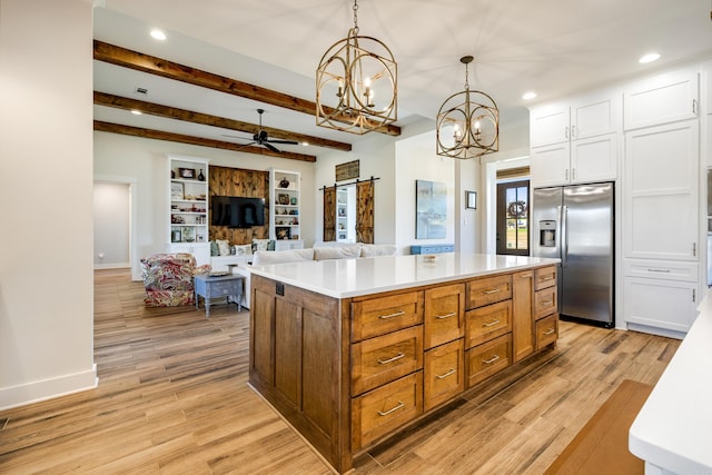 kitchen with beam ceiling, a barn door, stainless steel fridge with ice dispenser, decorative light fixtures, and a kitchen island