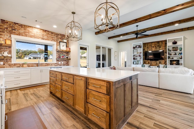 kitchen featuring brick wall, decorative light fixtures, light hardwood / wood-style flooring, white cabinets, and a center island