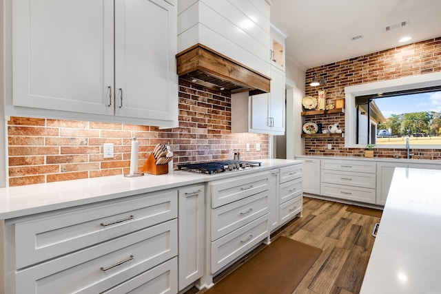 kitchen with white cabinets, tasteful backsplash, light hardwood / wood-style flooring, and stainless steel gas stovetop