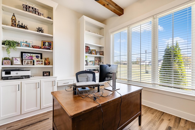 home office featuring beam ceiling, built in shelves, a healthy amount of sunlight, and light wood-type flooring