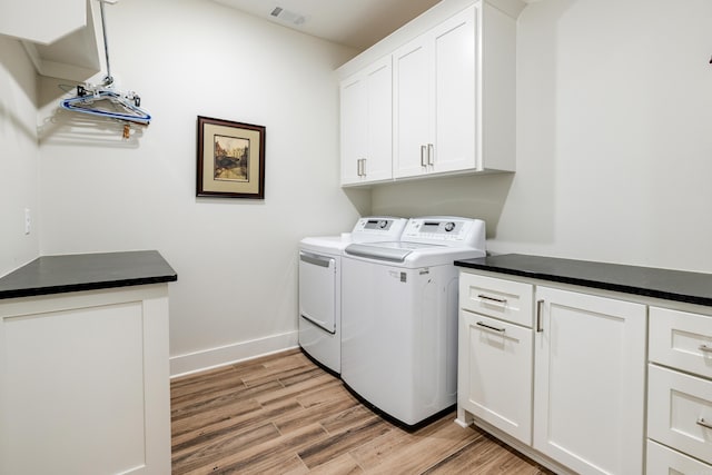 laundry area with washer and clothes dryer, cabinets, and light hardwood / wood-style floors