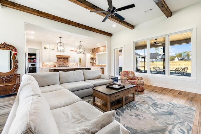 living room featuring a notable chandelier, beam ceiling, and light wood-type flooring