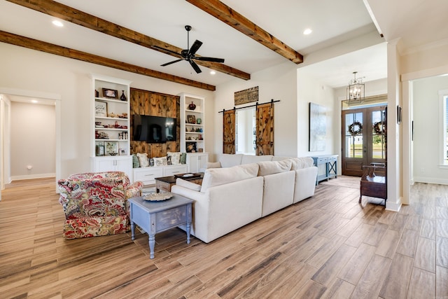 living room featuring a barn door, french doors, beamed ceiling, and ceiling fan with notable chandelier