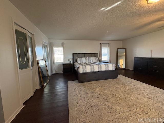 bedroom featuring multiple windows, dark hardwood / wood-style flooring, and a textured ceiling