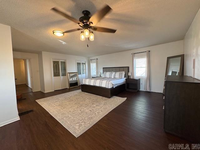 bedroom with ceiling fan, dark wood-type flooring, and a textured ceiling