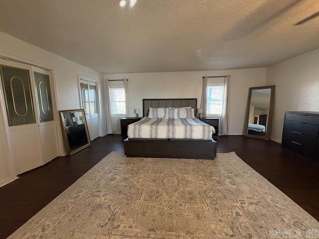 bedroom with multiple windows, dark wood-type flooring, and a textured ceiling