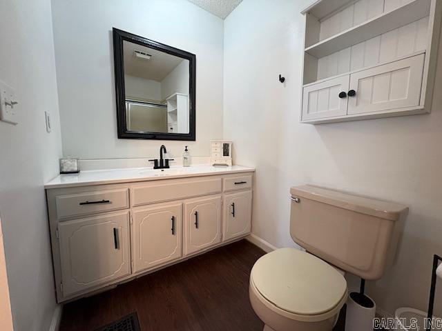 bathroom featuring vanity, toilet, wood-type flooring, and a textured ceiling