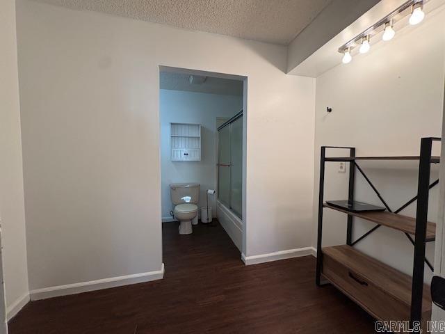 bathroom featuring shower / bath combination with glass door, wood-type flooring, a textured ceiling, and toilet