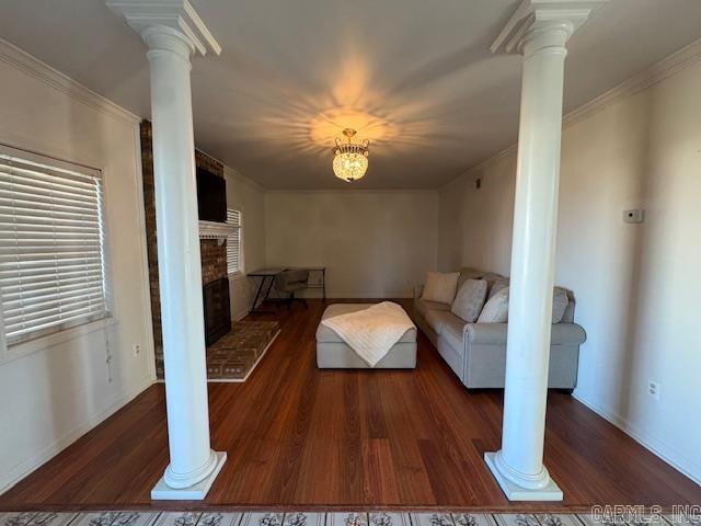 living room featuring a notable chandelier, crown molding, a fireplace, and dark wood-type flooring