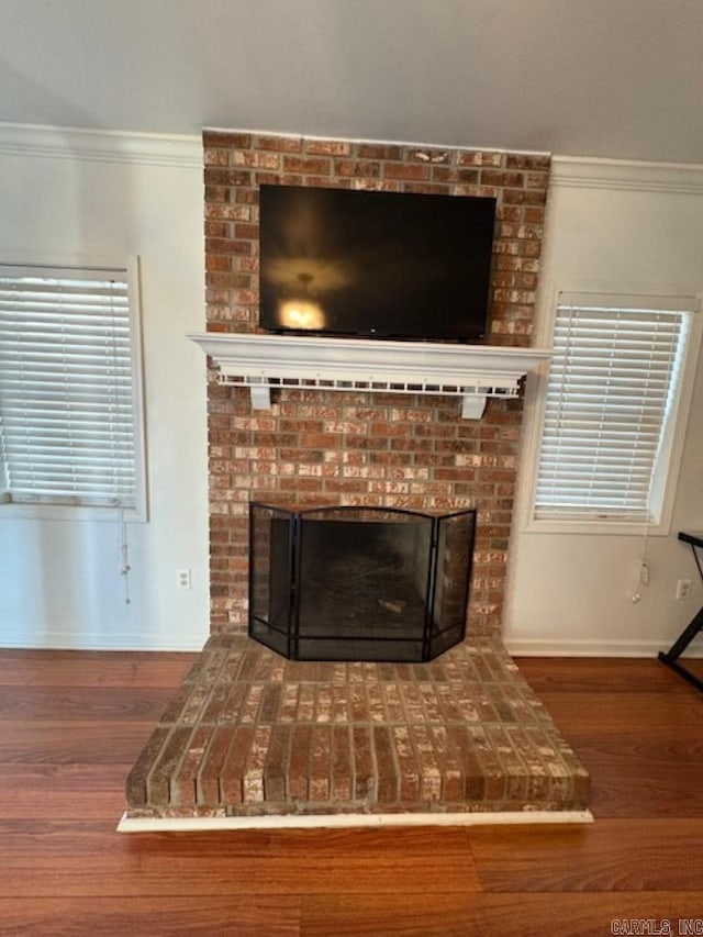 room details featuring hardwood / wood-style floors, ornamental molding, and a brick fireplace