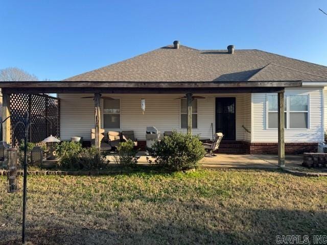 back of house featuring ceiling fan and a yard