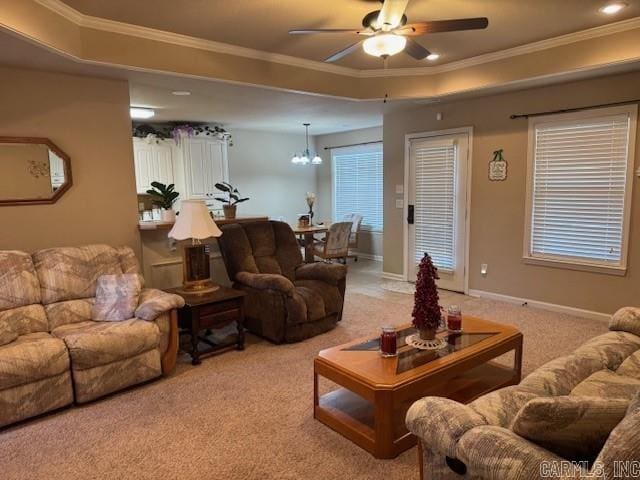 carpeted living room with ceiling fan with notable chandelier, ornamental molding, and a tray ceiling