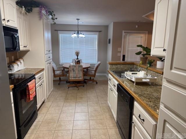 kitchen with white cabinetry, dark stone countertops, a chandelier, pendant lighting, and black appliances