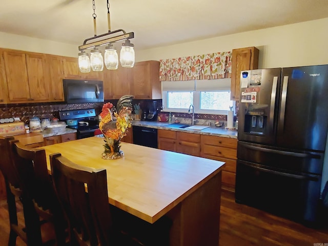 kitchen with pendant lighting, a center island, black appliances, sink, and tasteful backsplash