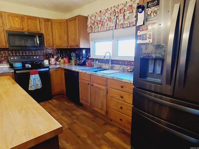 kitchen with butcher block countertops, dark hardwood / wood-style flooring, sink, and black appliances