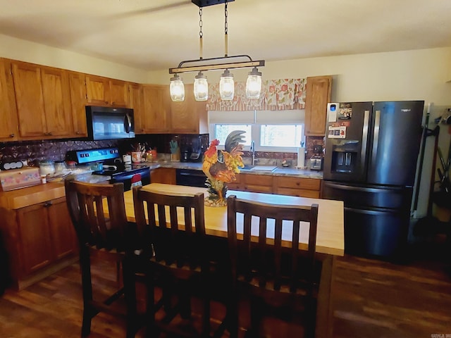 kitchen with dark hardwood / wood-style flooring, tasteful backsplash, sink, black appliances, and pendant lighting