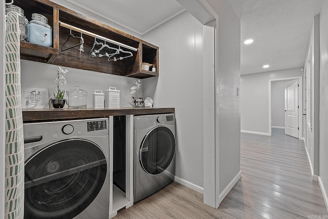 laundry room featuring washer and clothes dryer, a textured ceiling, and light hardwood / wood-style flooring