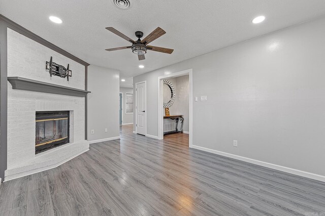 unfurnished living room featuring a fireplace, hardwood / wood-style floors, a textured ceiling, and ceiling fan