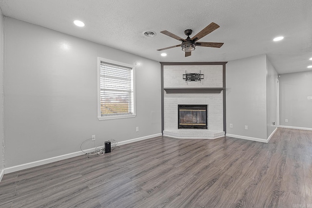 unfurnished living room featuring hardwood / wood-style floors, ceiling fan, a fireplace, and a textured ceiling