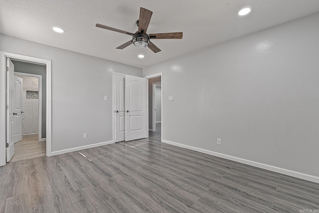 unfurnished bedroom featuring a textured ceiling, ensuite bath, light hardwood / wood-style flooring, and ceiling fan