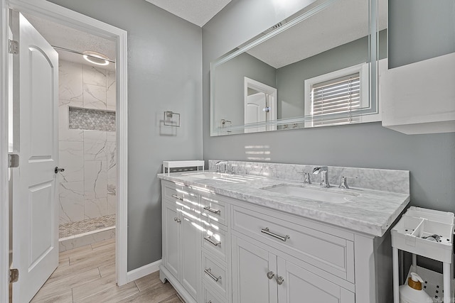 bathroom featuring tiled shower, a textured ceiling, and vanity