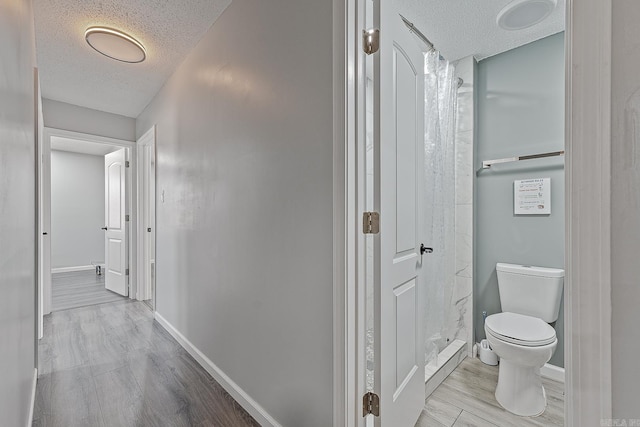 bathroom featuring a textured ceiling, toilet, and walk in shower