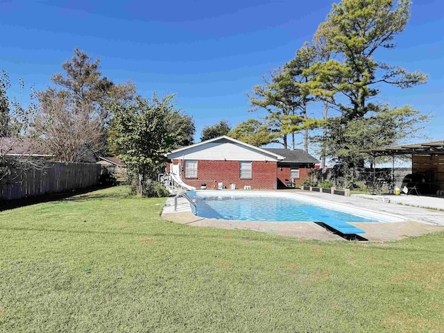 view of swimming pool with a diving board and a yard