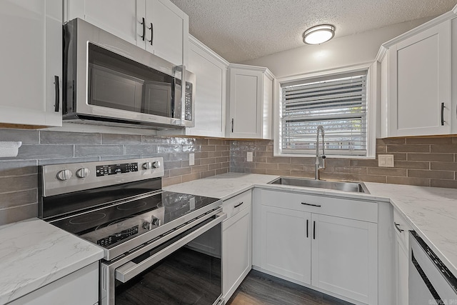 kitchen with light stone counters, sink, white cabinetry, and stainless steel appliances