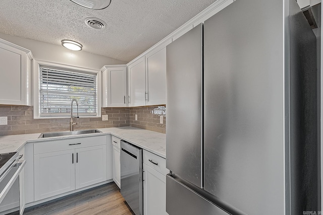 kitchen with white cabinets, light stone counters, sink, and appliances with stainless steel finishes