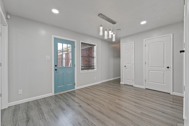 interior space with a textured ceiling, light hardwood / wood-style floors, and an inviting chandelier