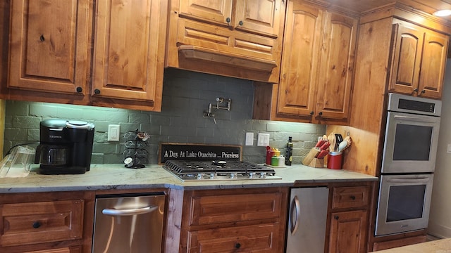 kitchen featuring backsplash, light stone counters, and appliances with stainless steel finishes