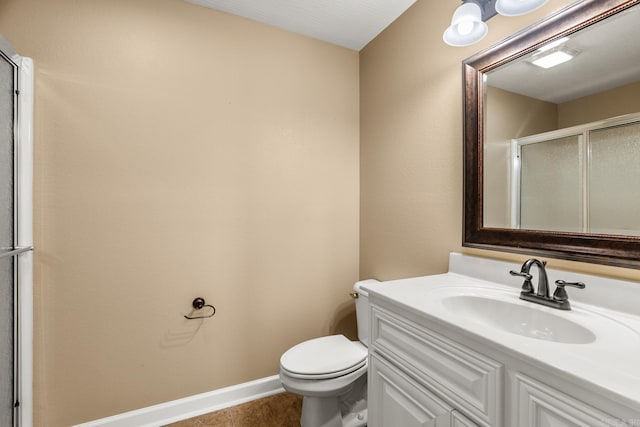 bathroom with tile patterned floors, a shower with door, vanity, and toilet