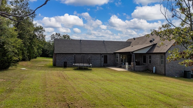 back of property with a yard, a patio, and a trampoline