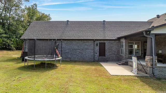 back of property featuring a patio area, a trampoline, and a yard